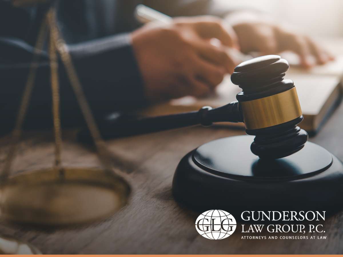  A wooden gavel on a desk with a blurred person writing in the background, symbolizing legal work in probate, trust administration, and estate planning