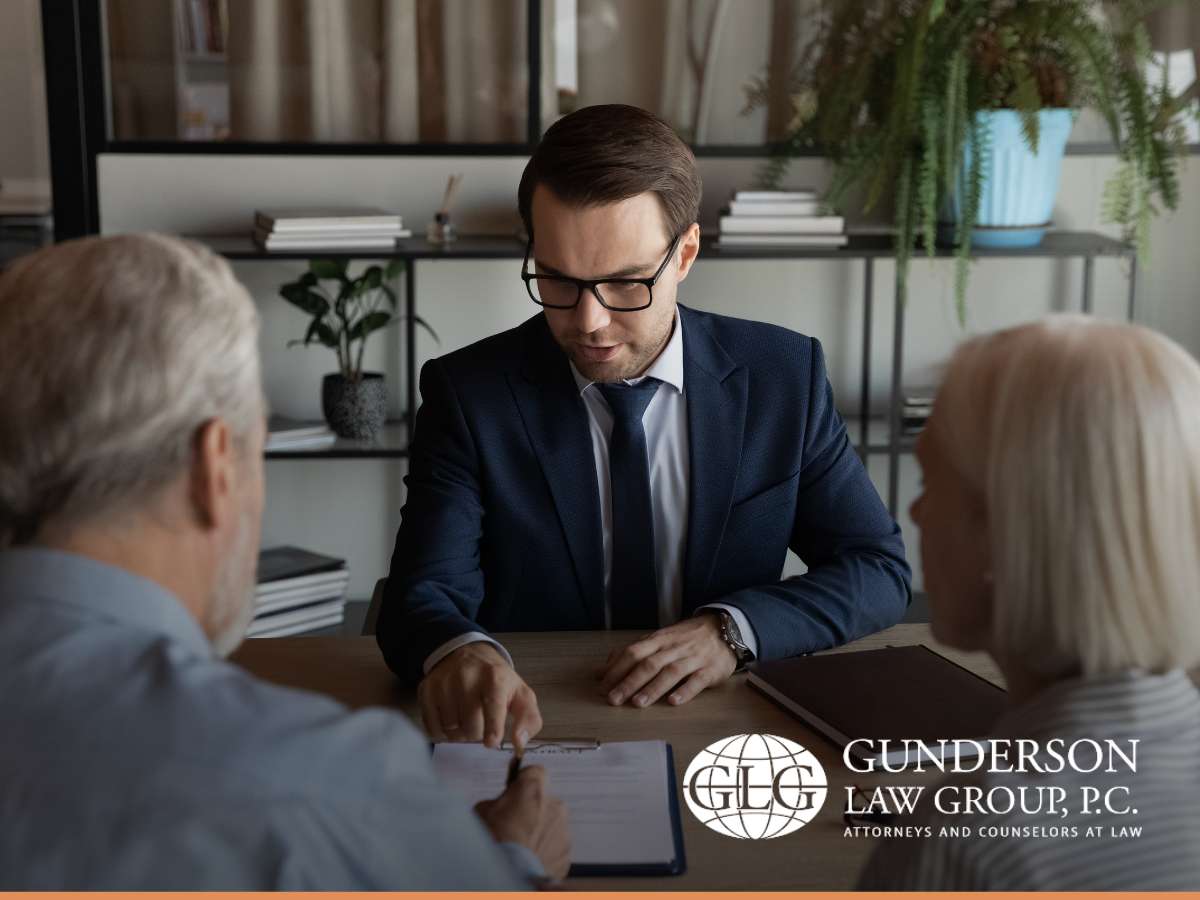 An estate planning lawyer discussing documents with an elderly couple at Gunderson Law Group office